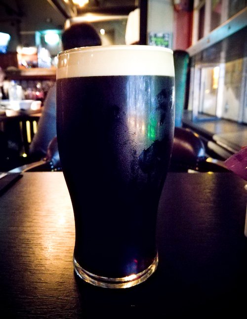 Dark stout beer on a pub background with colored lights from the environment